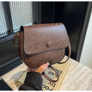 Close-up of vintage brown saddle bag showing fine leather texture and round clasp