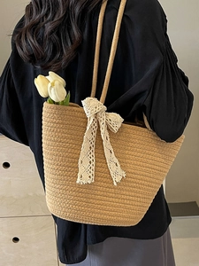 Large hand-woven straw tote bag with a white lace bow and twin handles for summer beach