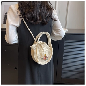 Modèle portant un sac en paille blanche avec nœud en dentelle et pendentif dessin