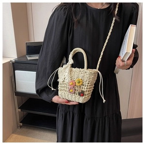 Detail of beige woven straw bag with floral embroidery and ladybug decor on strap