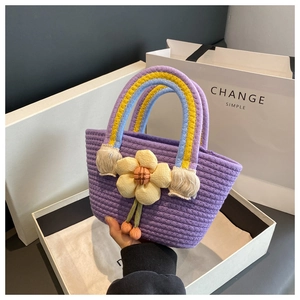Detailed shot of a purple knitted tote bag featuring a rainbow handle and yellow flower charm