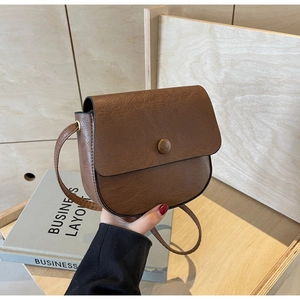 Close-up of vintage brown saddle bag with oil wax texture and decorative buckle detail