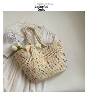 Détail d'un sac cabas en paille avec pompons colorés et nœud en dentelle sur une robe