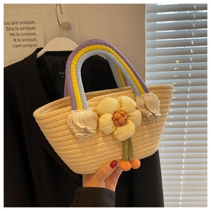 Detail of hand-woven straw bag with floral decoration and colorful braided handle