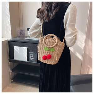 Detail of straw woven bag with 3D cherry accents and round handle for summer vacations