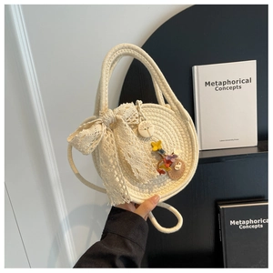 Détail du sac en paille rond avec nœud en dentelle et accessoires de pendentif en bois