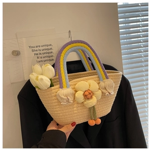 Detail of woven straw bag with rainbow handles and a yellow 3D floral accent