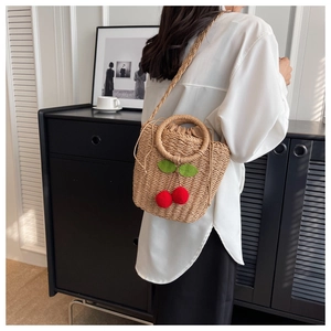 Detail of hand-woven straw shoulder bag with cherry motifs and drawstring lining