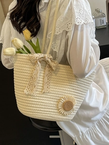Beige woven tote bag with lace bows and sunflower patches for beach vacation