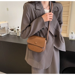 Retro brown saddle bag with natural texture shown in a trendy cafe lifestyle setting