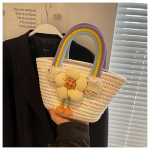 Detail of woven tote bag with rainbow handles, floral accent, and colorful wavy patterns