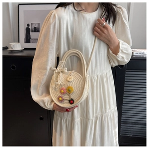 Detail der handgewebten runden Umhängetasche mit 3D-Häkelblumen und Spitzen-Schleife