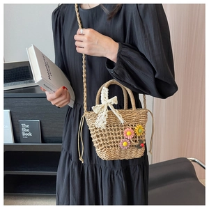 Detail of woven straw bag with lace bow, floral charms, and drawstring inner bag