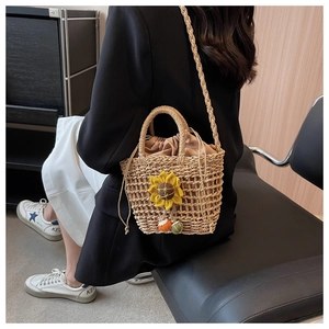 Detail of hand-woven straw crossbody bag with yellow flower charm and drawstring liner