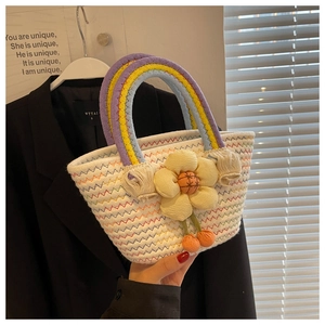 Detail of woven tote bag featuring rainbow handles and a large yellow flower ornament