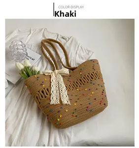 Détail du sac de plage tissé kaki avec pompons colorés et accent de nœud en dentelle
