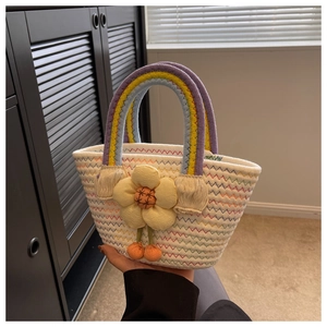 Detail of hand-woven mini tote bag featuring rainbow handles and a yellow flower charm