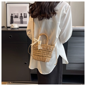 Detailed close-up of a handmade woven straw bag featuring a delicate white lace bow detail
