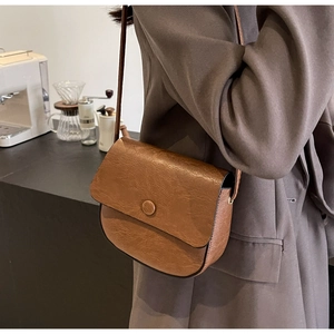 Brown semi-circular crossbody bag with retro texture shown on a stylish model
