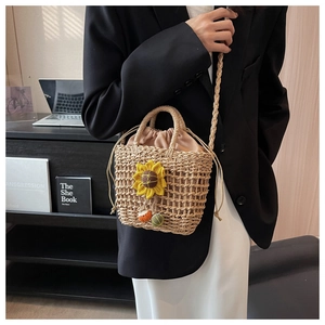 Detail of hand-woven straw bag with sunflower accent and colorful tassel charm