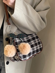 Crossbody bag with black and white plaid tweed and plush cherry charm on beige trench coat