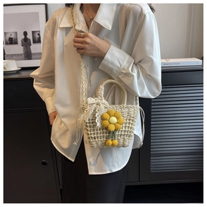 Close-up of handmade woven straw bag with sunflower accents and white lace bow detail