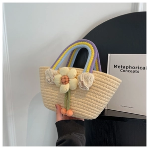 Detail of hand-woven straw bag with colorful striped handles and floral charm accessory