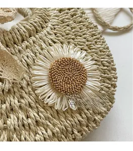 Close-up of woven straw bag detail featuring a white daisy flower and lace decoration