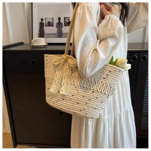 Détail d'un sac cabas tissé beige avec mouchetures colorées et un grand nœud en dentelle