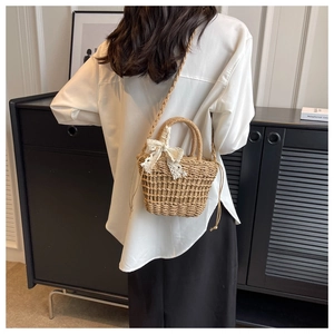 Detailed back view of handmade straw bucket bag with white lace bow and drawstring closure