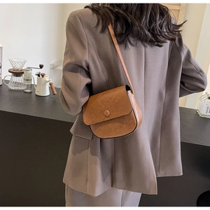 Detail of vintage brown leather saddle bag with flap closure and adjustable shoulder strap