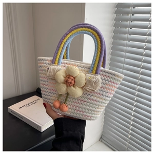 Close-up of a mini woven tote bag with a bright yellow sunflower and rainbow handle