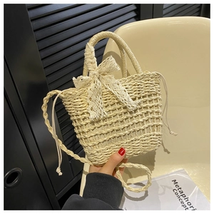 Detail of hand-woven beige straw bag with lace bow decoration and drawstring closure
