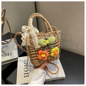 Detailed view of handmade straw bag featuring crochet flowers and delicate lace bow