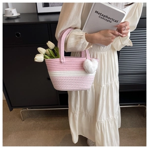 Detail der rosa-weiß gestreiften gewebten Beuteltasche mit Herzanhänger und weichem Griff