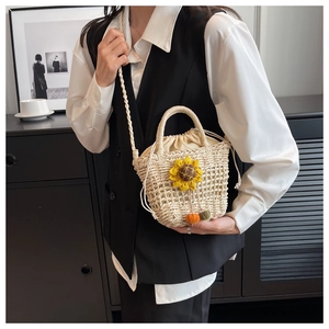 Detail of hand-woven straw crossbody bag with sunflower charm and drawstring liner