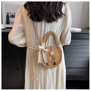 Detail einer runden Strohtasche mit bunten 3D-Blumen und einer Schleife aus Spitze