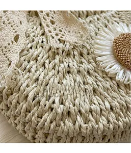 Detailed close-up of beige woven straw bag featuring floral lace and white sunflower accent