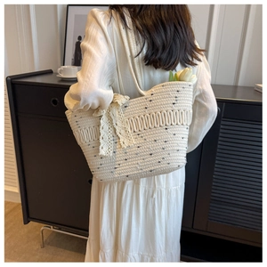 Détail du sac cabas tissé beige avec pois noirs et nœud en dentelle blanche dans un décor chic