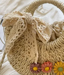 Detailed macro view of woven straw bag with lace bow and knit floral embellishments