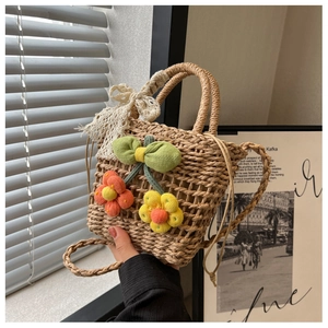 Detail of woven straw bag with colorful fabric flowers and white lace ribbon bow