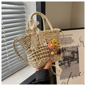 Detail of hand-woven straw beach bag with lace bow handle and 3D fabric flowers