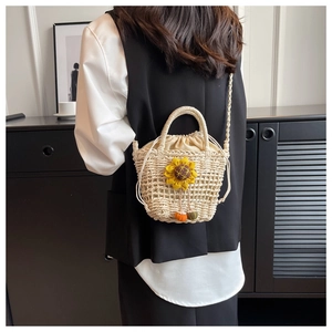 Detail of hand-woven straw beach bag with sunflower and pumpkin charms on a model