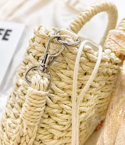 Detail of silver metal hook and woven handle on cream straw handbag with macro texture