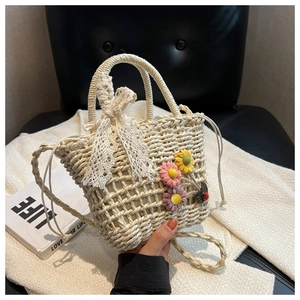 Detail of hand-woven straw bucket bag with lace bow, floral accents, and drawstring closure