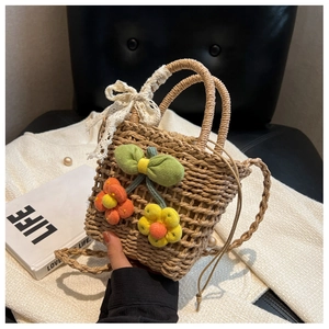 Detail of handmade straw tote bag with knit flowers and white lace ribbon handle