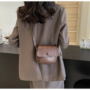 Close-up of a vintage dark brown saddle bag with textured leather worn by a model