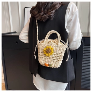 Detailed view of woven straw bucket bag with sunflower applique and drawstring closure