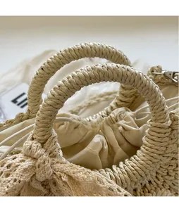 Detail of woven straw handbag featuring spiral handle, lace trim, and drawstring liner
