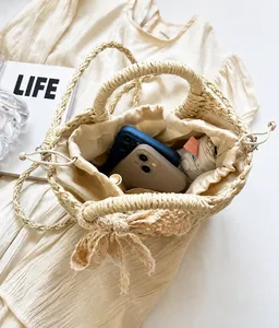 Detail view of woven straw bag with lace bow, showing inner capacity for smartphones